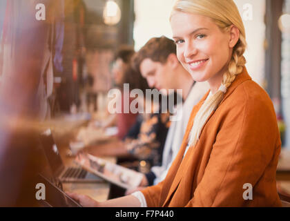 Portrait smiling blonde woman using digital tablet in cafe Stock Photo