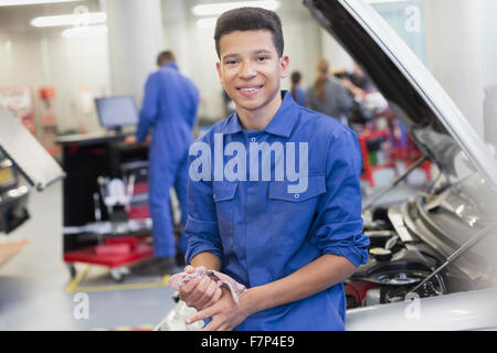 Portrait smiling mechanic leaning on car in auto repair shop Stock Photo