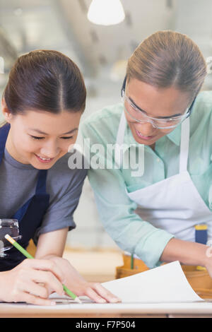 Female carpenters drafting blueprints in workshop Stock Photo