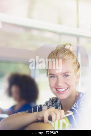 Portrait smiling blonde woman holding cell phone on bus Stock Photo
