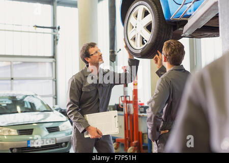 Mechanics examining and discussing tire in auto repair shop Stock Photo