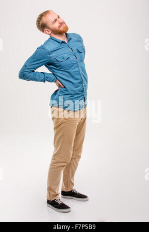Full length portrait of young handsome male with beard having a backache isolated over white background Stock Photo