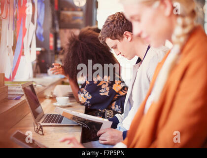 People working and drinking coffee in a row in cafe Stock Photo