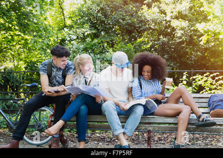 College students hanging out studying on park bench Stock Photo