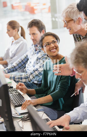 Students talking at computers in adult education classroom Stock Photo