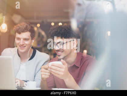 Friends drinking coffee and using laptop in cafe Stock Photo