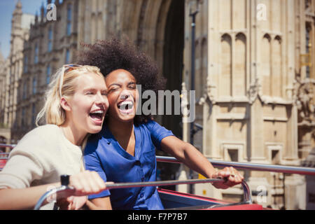 Enthusiastic friends laughing on double-decker bus in London Stock Photo