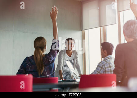 Teacher and students with hands raised in adult education class Stock Photo