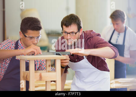 Focused carpenters measuring wood in workshop Stock Photo
