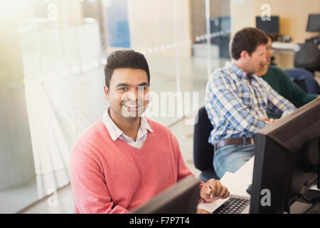 Portrait smiling adult education student at computer in classroom Stock Photo