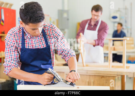 Carpenter using plane tool in workshop Stock Photo