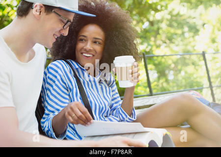 College students drinking coffee and studying in park Stock Photo
