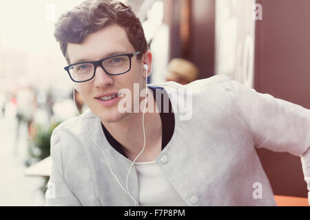 Portrait smiling man with eyeglasses listening to music on headphones Stock Photo