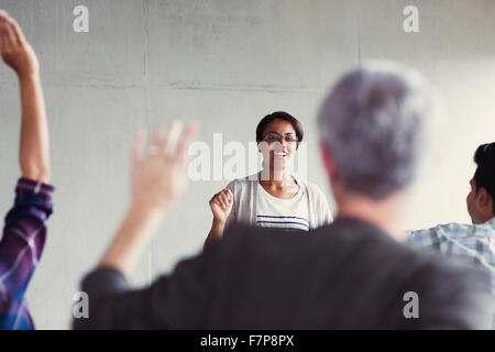 Teacher calling on students with hands raised in adult education classroom Stock Photo