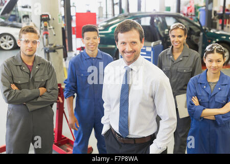 Portrait confident businessman and mechanics in auto repair shop Stock Photo