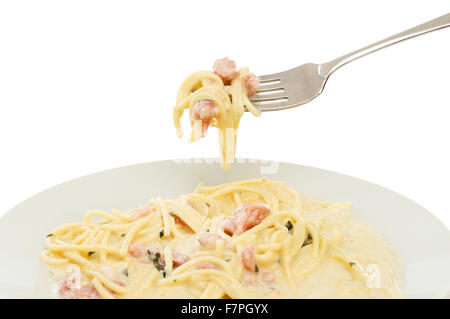 Spaghetti carbonara in a bowl and on a fork against a white background Stock Photo