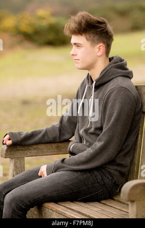 Teenage boy sitting on a park bench Stock Photo