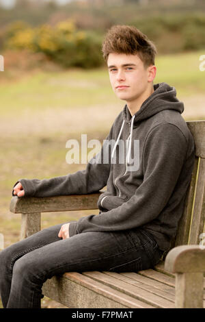 Teenage boy sitting on a park bench Stock Photo