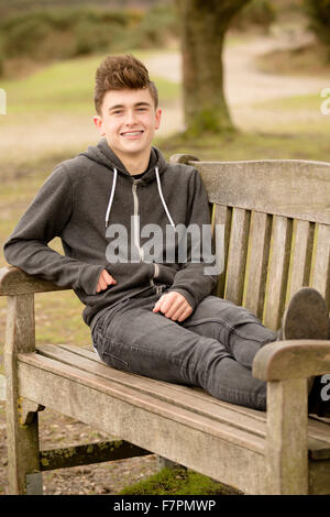 Teenage boy sitting on a park bench Stock Photo