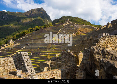 Machu Picchu illuminated by the last sunlight. Wide angle view from below over the glowing terraces with scenic sky. Machu Picch Stock Photo