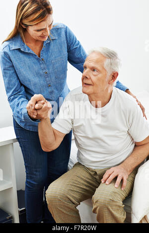 Daughter helping old senior man getting up from bed Stock Photo