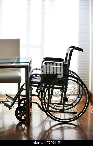 Empty wheelchair on a table in a nursing home Stock Photo