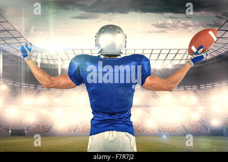 Composite image of full length rear view of american football player holding ball Stock Photo