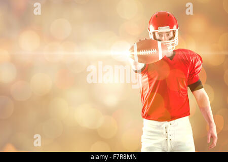 Composite image of portrait of american football player showing football to camera Stock Photo