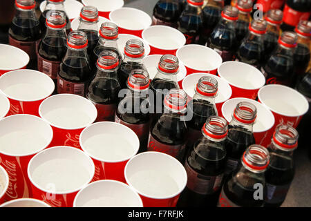 Open plastic Coca Cola bottles and throwaway cups with sparkling water at event Stock Photo