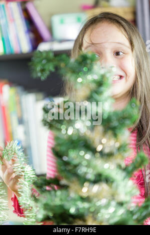 Young girl happily decorating Christmas tree Stock Photo