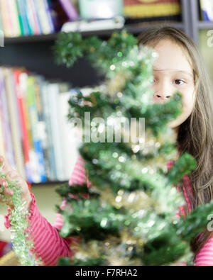 Young girl happily decorating Christmas tree Stock Photo