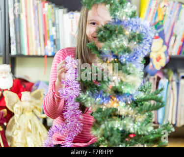 Young girl happily decorating Christmas tree Stock Photo