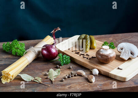 Long Noodles Linguine, pickled cucumbers gherkins, Champignon mushrooms, herbs, spices and vegetables on wooden table Stock Photo