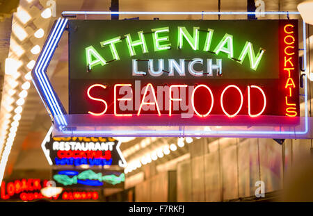 Seattle, Washington, USA. 23rd Nov, 2015. Seattle's Pike Place Market began in 1907 and was designed to benefit small farmers and fisherman as well as the makers of other goods. Pike Place Market located along the Seattle waterfront along Elliott Bay and is comprised of not along Pike Place, a city street, but also several floors below as well. The Pike Place Market has undergone some changes over the years but has retained its old world charm bringing tourists from all over the world. ------- In the photo, inside Pike Place Market, neon signs with fish themes mark out specialty foods as sho Stock Photo