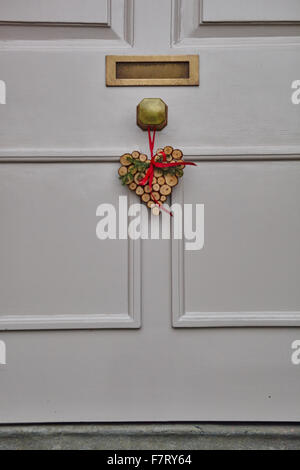 Heart shaped Christmas Wreath on white front door Stock Photo