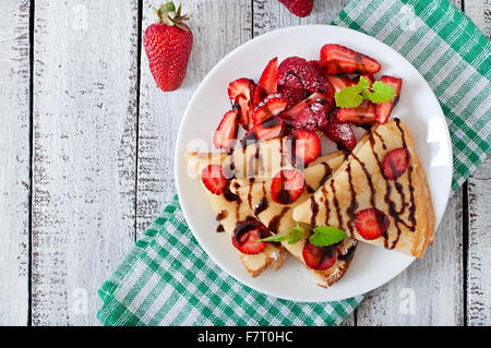 Pancakes with strawberries and chocolate decorated with mint leaf. Top view Stock Photo