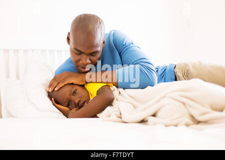 loving African father taking care of his ill son on bed Stock Photo