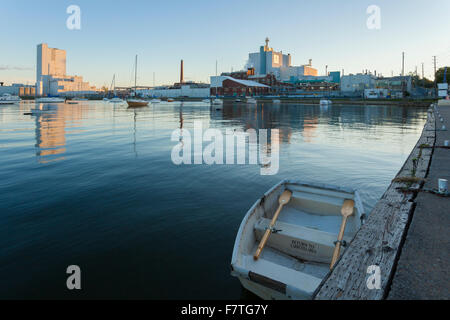 A small rowboat with the Cameco Fuel Manufacturing Inc. factory in the background at the Port Hope Harbour. Port Hope, Ontario. Stock Photo