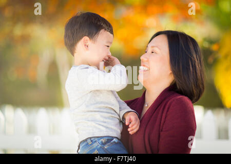 Happy Chinese Mom Having Fun and Holding Her Mixed Race Little Boy. Stock Photo