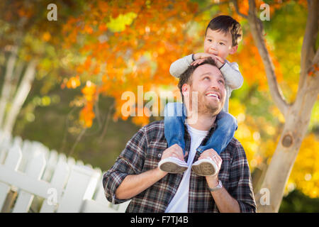 Happy Mixed Race Boy Riding Piggyback on Shoulders of Caucasian Father. Stock Photo