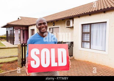handsome young African man with sold sign in front of his house Stock Photo