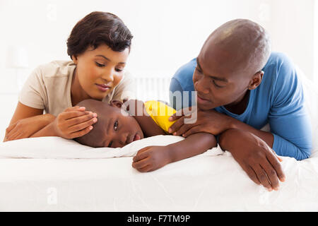 portrait of caring African parents and sick son lying on the bed Stock Photo