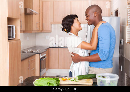 lovely young African couple embracing in kitchen Stock Photo