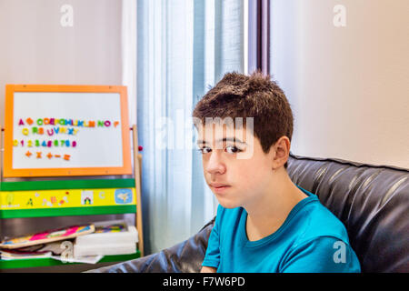 Caucasian teenage boy waits in the waiting room in the dental clinic near a board with some magnetic letters Stock Photo