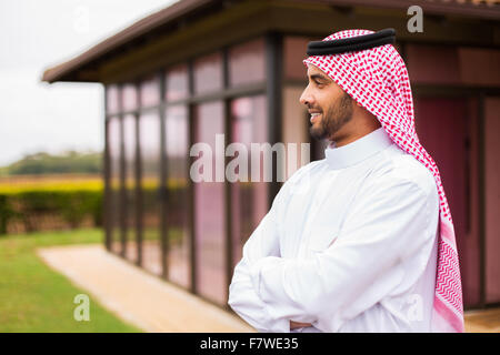 thoughtful Arabian man standing in front of his house Stock Photo