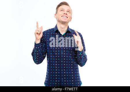 Positive handsome young male in plaid shirt  looking up and  pointing up with both hands over white background Stock Photo