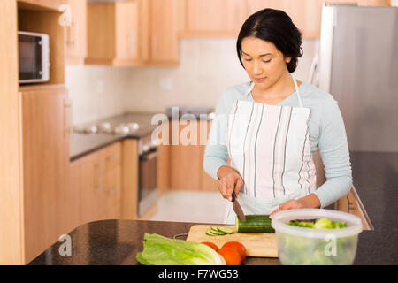 pretty Indian woman preparing dinner in home kitchen Stock Photo