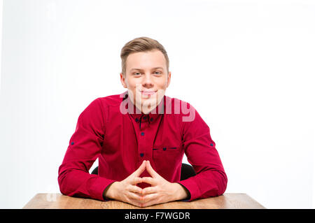 Content handsome young man in red shirt sitting and smiling isolated over white background Stock Photo