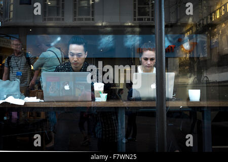Young man and woman using Apple Mac computer in a cafe, Birmingham, UK Stock Photo