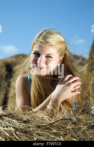 Country girl on fresh hay in summer Stock Photo